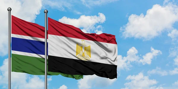 Bandera de Gambia y Egipto ondeando en el viento contra el cielo azul nublado blanco juntos. Concepto diplomático, relaciones internacionales . — Foto de Stock