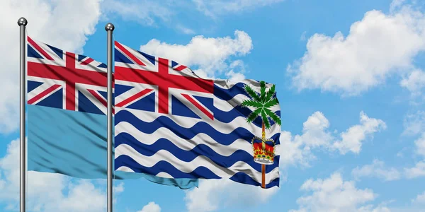 Bandera de Fiji y del Territorio Británico del Océano Índico ondeando en el viento contra el cielo azul nublado blanco juntos. Concepto diplomático, relaciones internacionales . — Foto de Stock