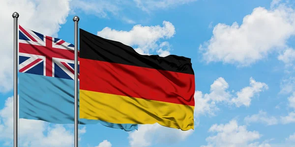 Fidzsi-szigetek és Németország zászló integetett a szél ellen, fehér felhős kék ég együtt. Diplomáciai koncepció, nemzetközi kapcsolatok. — Stock Fotó