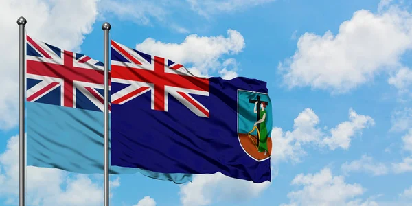 Фіджі і Монтмонрат прапор розмахував вітром проти білого хмарного синього неба разом. Концепція дипломатії, міжнародні відносини. — стокове фото