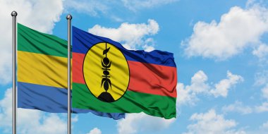 Gabon ve Yeni Kaledonya bayrağı birlikte beyaz bulutlu mavi gökyüzüne karşı rüzgarda sallayarak. Diplomasi kavramı, uluslararası ilişkiler.