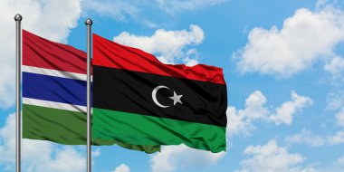 Gambiya ve Libya bayrağı birlikte beyaz bulutlu mavi gökyüzüne karşı rüzgarsal sallayarak. Diplomasi kavramı, uluslararası ilişkiler.