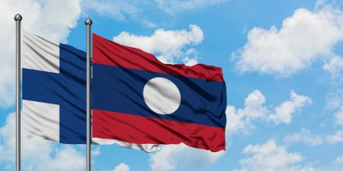 Finlandiya ve Laos bayrağı birlikte beyaz bulutlu mavi gökyüzüne karşı rüzgarda sallayarak. Diplomasi kavramı, uluslararası ilişkiler.