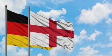 Almanya ve İngiltere bayrağı birlikte beyaz bulutlu mavi gökyüzüne karşı rüzgarsal sallayarak. Diplomasi kavramı, uluslararası ilişkiler.