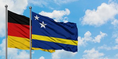 Almanya ve Curacao bayrağı birlikte beyaz bulutlu mavi gökyüzüne karşı rüzgarda sallayarak. Diplomasi kavramı, uluslararası ilişkiler.