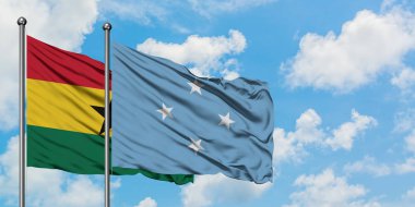 Gana ve Mikronezya bayrağı birlikte beyaz bulutlu mavi gökyüzüne karşı rüzgarda sallayarak. Diplomasi kavramı, uluslararası ilişkiler.