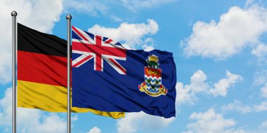 Almanya ve Cayman Adaları bayrağı birlikte beyaz bulutlu mavi gökyüzüne karşı rüzgarsal sallayarak. Diplomasi kavramı, uluslararası ilişkiler.