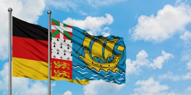 Almanya ve Saint Pierre ve Miquelon bayrağı birlikte beyaz bulutlu mavi gökyüzüne karşı rüzgarda sallayarak. Diplomasi kavramı, uluslararası ilişkiler.