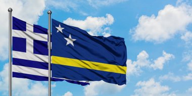 Yunanistan ve Curacao bayrağı birlikte beyaz bulutlu mavi gökyüzüne karşı rüzgarda sallayarak. Diplomasi kavramı, uluslararası ilişkiler.