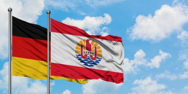 Almanya ve Fransız Polinezyası bayrağı birlikte beyaz bulutlu mavi gökyüzüne karşı rüzgarda sallayarak. Diplomasi kavramı, uluslararası ilişkiler.