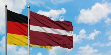 Almanya ve Letonya bayrağı birlikte beyaz bulutlu mavi gökyüzüne karşı rüzgarsal sallayarak. Diplomasi kavramı, uluslararası ilişkiler.