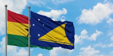 Gana ve Tokelau bayrağı birlikte beyaz bulutlu mavi gökyüzüne karşı rüzgarda sallayarak. Diplomasi kavramı, uluslararası ilişkiler.
