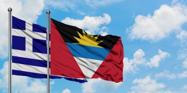 Yunanistan ve Antigua ve Barbuda bayrağı birlikte beyaz bulutlu mavi gökyüzüne karşı rüzgarda sallayarak. Diplomasi kavramı, uluslararası ilişkiler.