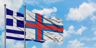 Yunanistan ve Faroe Adaları bayrağı birlikte beyaz bulutlu mavi gökyüzüne karşı rüzgarsal sallayarak. Diplomasi kavramı, uluslararası ilişkiler.