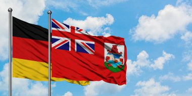 Almanya ve Bermuda bayrağı birlikte beyaz bulutlu mavi gökyüzüne karşı rüzgarda sallayarak. Diplomasi kavramı, uluslararası ilişkiler.