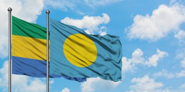 Gabon ve Palau bayrağı birlikte beyaz bulutlu mavi gökyüzüne karşı rüzgarda sallayarak. Diplomasi kavramı, uluslararası ilişkiler.
