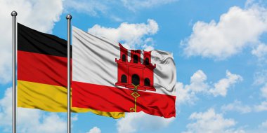 Almanya ve Cebelitarık bayrağı birlikte beyaz bulutlu mavi gökyüzüne karşı rüzgarsal sallayarak. Diplomasi kavramı, uluslararası ilişkiler.