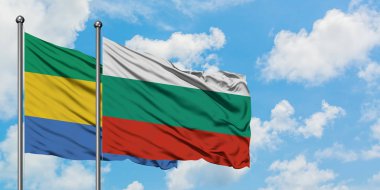 Gabon ve Bulgaristan bayrağı birlikte beyaz bulutlu mavi gökyüzüne karşı rüzgarda sallayarak. Diplomasi kavramı, uluslararası ilişkiler.