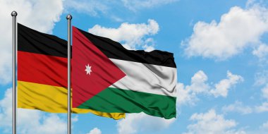 Almanya ve Ürdün bayrağı birlikte beyaz bulutlu mavi gökyüzüne karşı rüzgarsal sallayarak. Diplomasi kavramı, uluslararası ilişkiler.