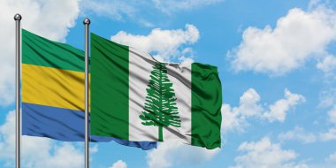 Gabon ve Norfolk Adası bayrağı birlikte beyaz bulutlu mavi gökyüzüne karşı rüzgarda sallayarak. Diplomasi kavramı, uluslararası ilişkiler.