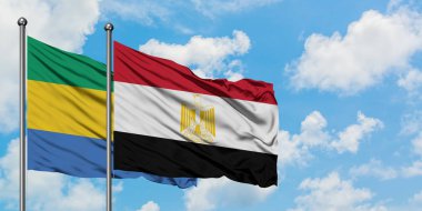 Gabon ve Mısır bayrağı birlikte beyaz bulutlu mavi gökyüzüne karşı rüzgarda sallayarak. Diplomasi kavramı, uluslararası ilişkiler.