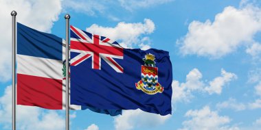 Dominik Cumhuriyeti ve Cayman Adaları bayrağı birlikte beyaz bulutlu mavi gökyüzüne karşı rüzgarda sallayarak. Diplomasi kavramı, uluslararası ilişkiler.