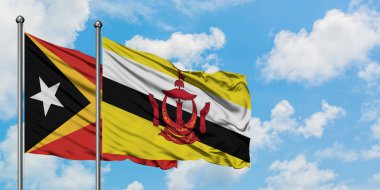 Doğu Timor ve Brunei bayrağı birlikte beyaz bulutlu mavi gökyüzüne karşı rüzgarda sallayarak. Diplomasi kavramı, uluslararası ilişkiler.