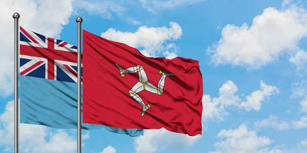 Bandera de Fiji y Isla de Man ondeando en el viento contra el cielo azul nublado blanco juntos. Concepto diplomático, relaciones internacionales . — Foto de Stock