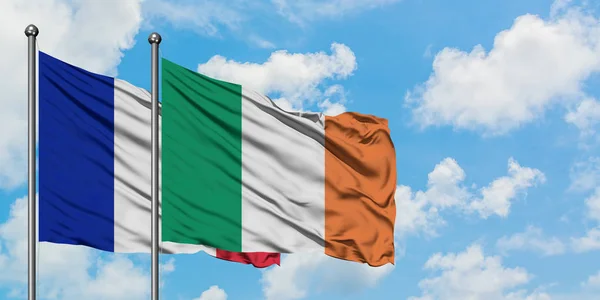 Francie a Irská vlajka mávajících větrem proti bílé zatažené modré obloze dohromady. Diplomacie, mezinárodní vztahy. — Stock fotografie