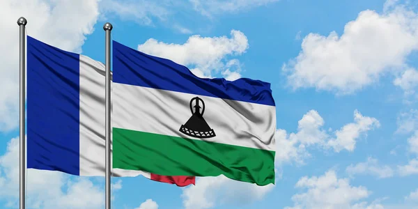 Franciaország és Lesotho zászló integetett a szél ellen, fehér felhős kék ég együtt. Diplomáciai koncepció, nemzetközi kapcsolatok. — Stock Fotó