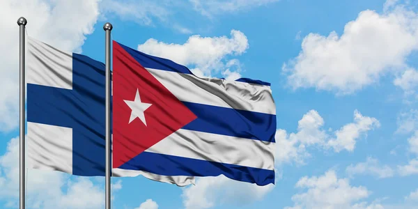 Finnland und Kuba wehen gemeinsam im Wind vor dem wolkenverhangenen blauen Himmel. Diplomatie-Konzept, internationale Beziehungen. — Stockfoto