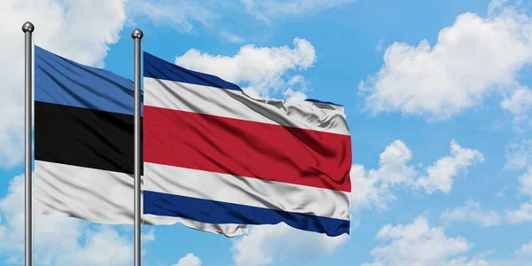 Estonia e Costa Rica sventolano bandiera nel vento contro bianco cielo blu nuvoloso insieme. Concetto di diplomazia, relazioni internazionali . — Foto Stock