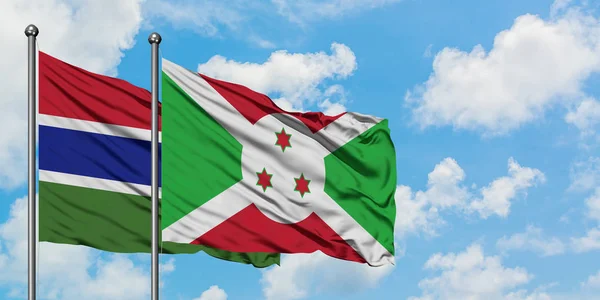 Gambia a Burundská vlajka mávali ve větru proti bíle zatažené modré obloze. Diplomacie, mezinárodní vztahy. — Stock fotografie