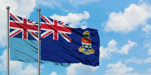 Fiji en Caymaneilanden vlag zwaaien in de wind tegen witte bewolkte blauwe hemel samen. Diplomatie concept, internationale betrekkingen. — Stockfoto