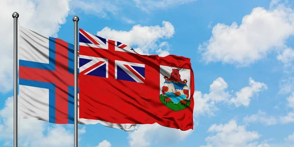 Islas Feroe y la bandera de las Bermudas ondeando en el viento contra el cielo azul nublado blanco juntos. Concepto diplomático, relaciones internacionales . —  Fotos de Stock