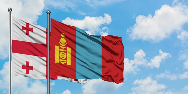 Bandera de Georgia y Mongolia ondeando en el viento contra el cielo azul nublado blanco juntos. Concepto diplomático, relaciones internacionales . — Foto de Stock