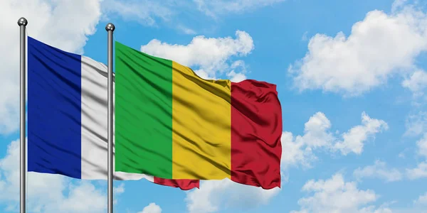 Francia e bandiera del Mali sventolano nel vento contro il bianco cielo blu nuvoloso insieme. Concetto di diplomazia, relazioni internazionali . — Foto Stock