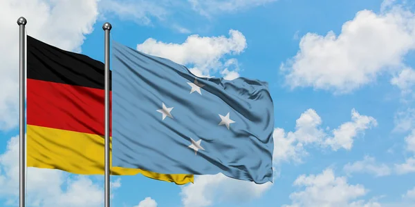 Deutschland und Mikronesien wehen gemeinsam im Wind vor dem wolkenverhangenen blauen Himmel. Diplomatie-Konzept, internationale Beziehungen. — Stockfoto