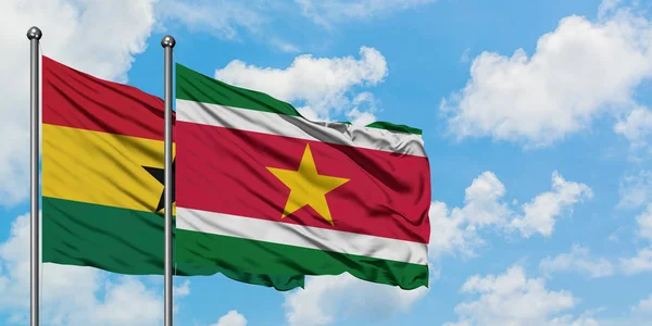 Bandera de Ghana y Surinam ondeando en el viento contra el cielo azul nublado blanco juntos. Concepto diplomático, relaciones internacionales . — Foto de Stock
