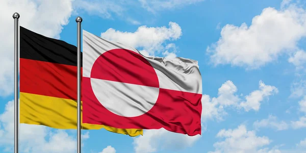 Tyskland och Grönland sjunker vifta i vinden mot vit grumlig blå himmel tillsammans. Diplomatisk koncept, internationella relationer. — Stockfoto