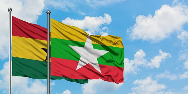 Bandera de Ghana y Myanmar ondeando en el viento contra el cielo azul nublado blanco juntos. Concepto diplomático, relaciones internacionales . — Foto de Stock