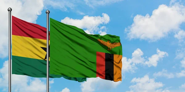 Ghana e Zambia sventolano nel vento contro il bianco cielo azzurro nuvoloso insieme. Concetto di diplomazia, relazioni internazionali . — Foto Stock
