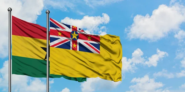 Bandera de Ghana y Niue ondeando en el viento contra el cielo azul nublado blanco juntos. Concepto diplomático, relaciones internacionales . — Foto de Stock