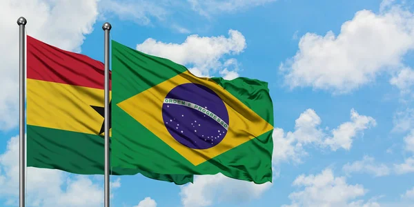 Bandera de Ghana y Brasil ondeando en el viento contra el cielo azul nublado blanco juntos. Concepto diplomático, relaciones internacionales . — Foto de Stock