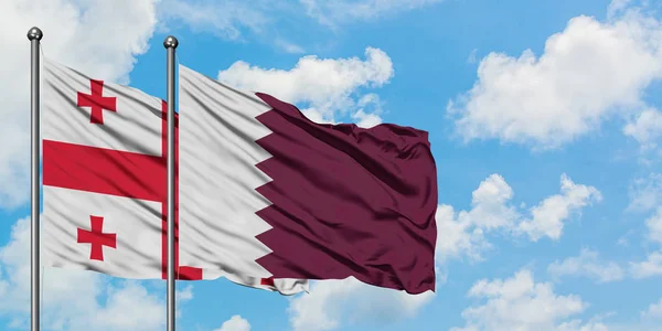 Georgien och Qatar flagga viftande i vinden mot vit grumlig blå himmel tillsammans. Diplomatisk koncept, internationella relationer. — Stockfoto