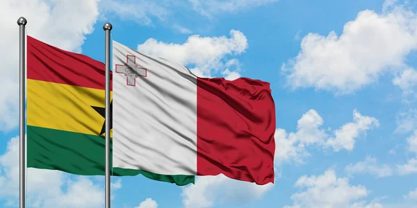 Bandera de Ghana y Malta ondeando en el viento contra el cielo azul nublado blanco juntos. Concepto diplomático, relaciones internacionales . — Foto de Stock