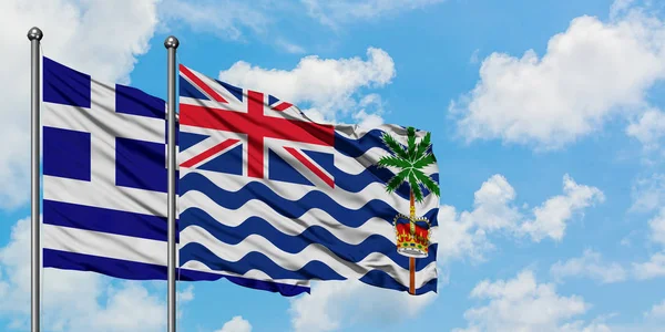 Bandera de Grecia y del Territorio Británico del Océano Índico ondeando en el viento contra el cielo azul nublado blanco juntos. Concepto diplomático, relaciones internacionales . — Foto de Stock
