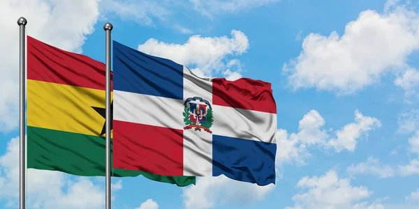 Bandera de Ghana y República Dominicana ondeando en el viento contra el cielo azul nublado blanco juntos. Concepto diplomático, relaciones internacionales . — Foto de Stock