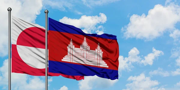 Gemeinsam wehen grönländische und kambodschanische Flaggen im Wind gegen den wolkenverhangenen blauen Himmel. Diplomatie-Konzept, internationale Beziehungen. — Stockfoto