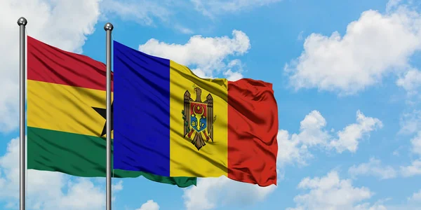 Bandera de Ghana y Moldavia ondeando en el viento contra el cielo azul nublado blanco juntos. Concepto diplomático, relaciones internacionales . — Foto de Stock